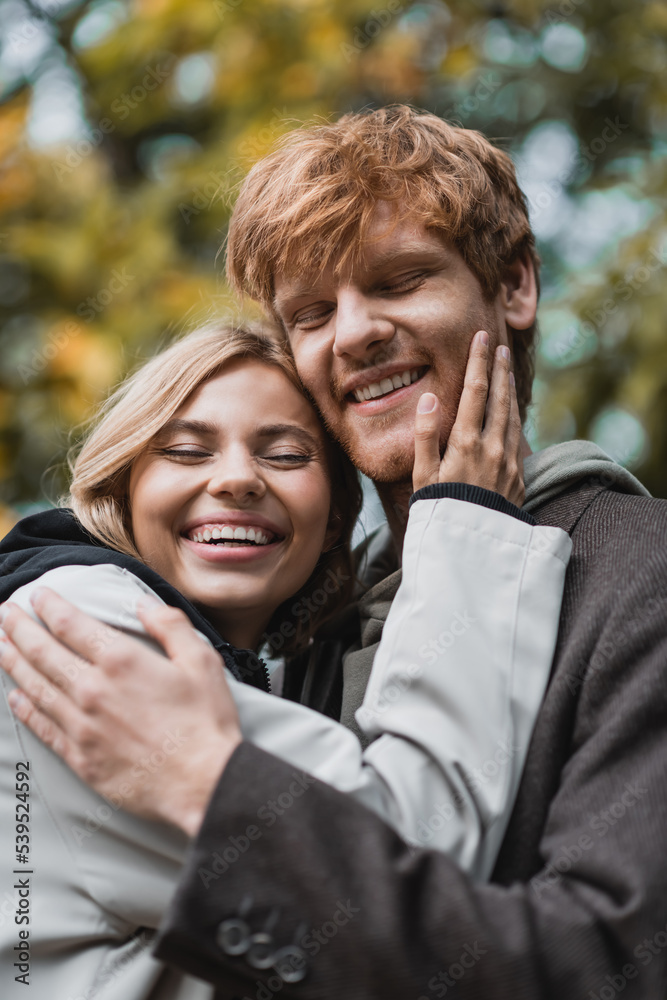 joyful young couple with closed eyes embracing each other during date.