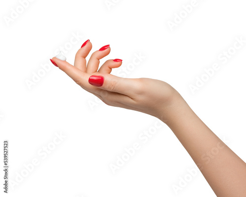 A drop of thick white hand cream on the finger of a woman's hand. Groomed hands, natural short nails with red nail polish.