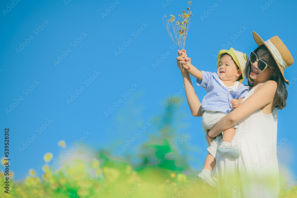 mother with little child in white blooming garden. woman with son in green leaves,happy family outdoors in spring