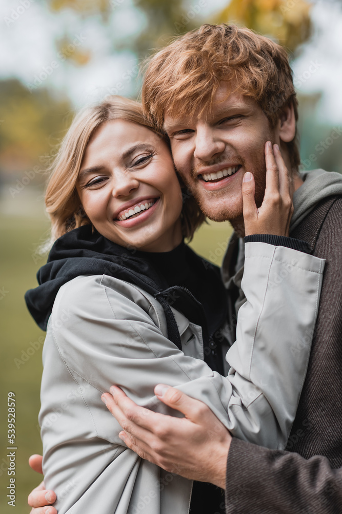 portrait of happy couple in coats looking at camera while embracing during date. portrait of happy couple in coats looking at camera while embracing during date.