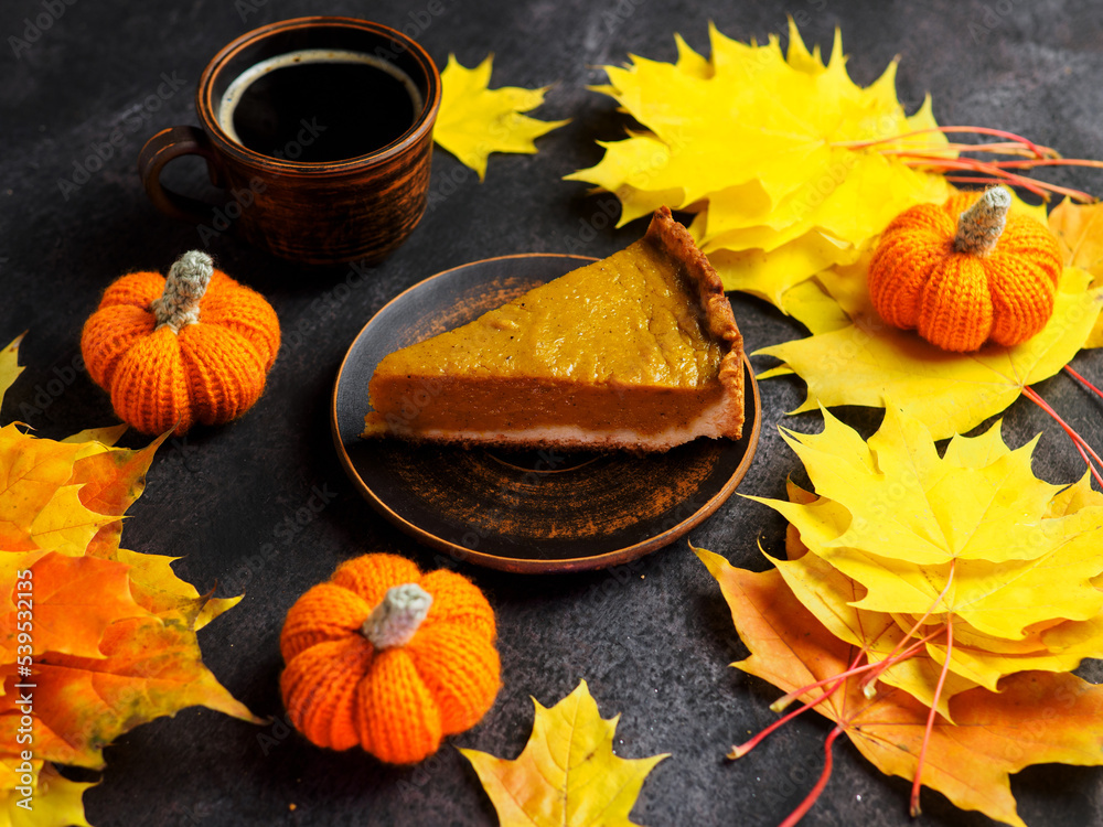 Traditional pumpkin pie for Thanksgiving and a cup of espresso coffee on the table with yellow maple leaves. Top view