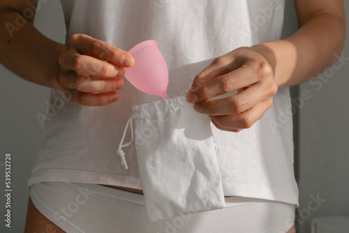 Female hands take menstrual cup out of her bag photo