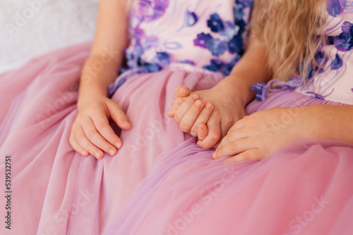 Two sisters hold hands close up.