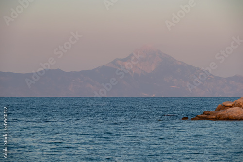 Beautiful panoramic view of holy Mount Athos seen from Karydi beach, peninsula Sithonia, Chalkidiki (Halkidiki), Greece, Europe. Summer vacation at Aegean Mediterranean Sea. Rock formations in the bay photo