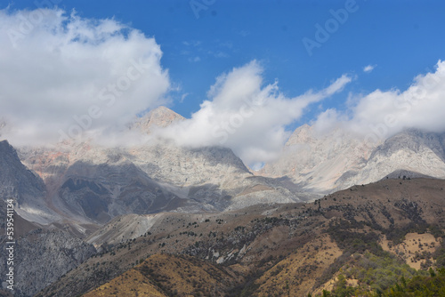  panoramic view of the mountain range in the clouds with blue sky on the background in Arslanbob in Kyrgyzstan