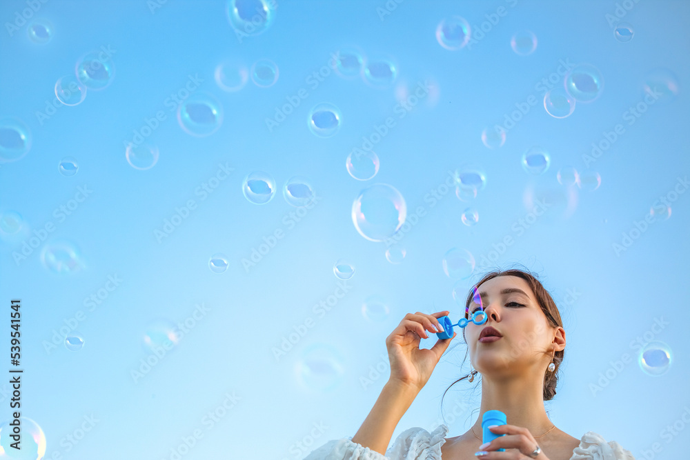 The girl blows soap bubbles against the blue sky. The girl blows soap bubbles against the blue sky.