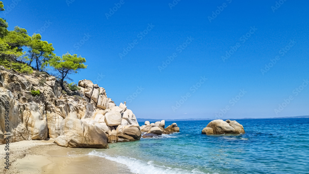Panoramic view on calm Fava sand beach near Vourvourou, Greek peninsula Sithonia, Chalkidiki (Halkidiki), Greece, Europe. Summer vacation at Aegean Mediterranean Sea. Unique natural rock formations