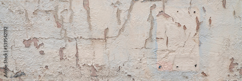 old plaster wall background and texture with holes and cracks and paint peeling off, panoramic web banner