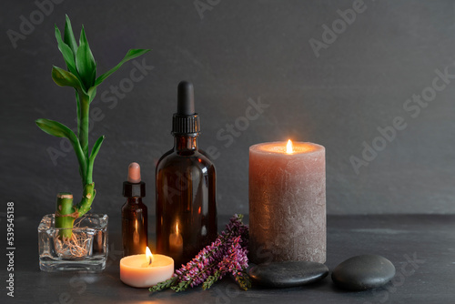 Beauty still life with oils  candles  bamboo and stones  slate background. Spa concept  relaxation  skin care.
