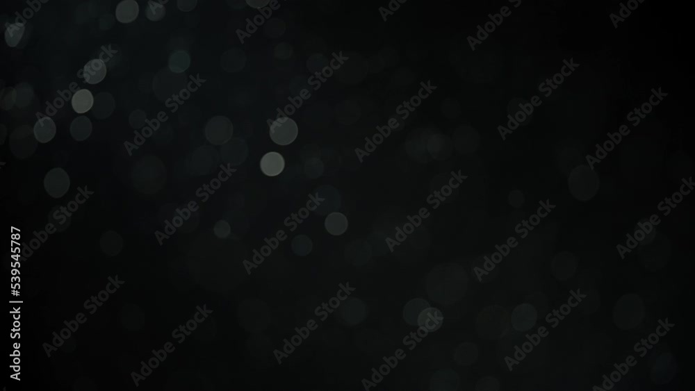 Abstract bokeh dust particles floating in the air on black background. Slow motion. Abstract bokeh dust particles floating in the air on black background. Slow motion.