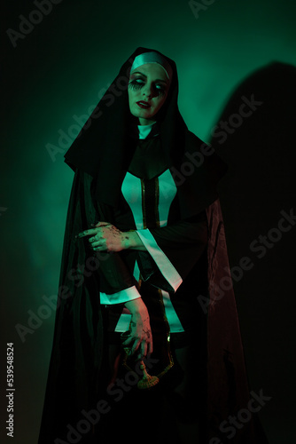 Halloween. Portrait of a scary devilish nun eyes looking at camera on a black and green background.
