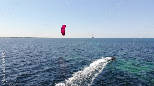 Aerial view of a young caucasian woman kitesurfer rides her kite and catboard in the open sea on a sunny day. To enjoy life. Active sports