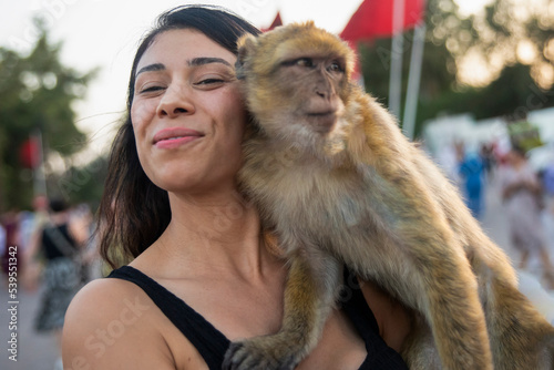 Canvas Print Young tourist enjoying a monkey in Jemaa el Fna square in Marrakech in Morocco, these are animals that interact with visitors