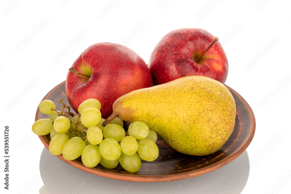 Two red apples, a pear and grapes on a clay plate, macro, isolated on a white background. Two red apples, a pear and grapes on a clay plate, macro, isolated on a white background.