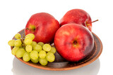 Three red apples and grapes on a clay plate, macro, isolated on white background.