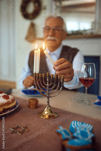 Close up of Jewish mature man lights traditional candles during festival of lights. photo