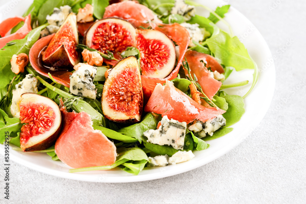 Healthy food recipe - salad with fresh fig, blue cheese, prosciutto, arugula and spinach on white table background with copy space. Lunch idea. Selective focus Healthy food recipe - salad with fresh fig, blue cheese, prosciutto, arugula and spinach on white table background with copy space. Lunch idea. Selective focus
