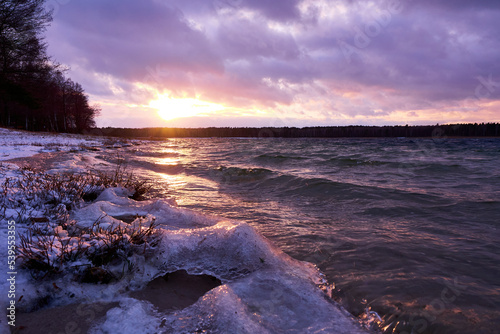 Pink sunset over frozen lake. Sunset reflection in frozen lake.