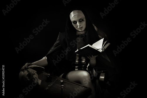 Принти на полотні An evil cursed nun with a notebook and a cross in her hands looks at the camera on a black background