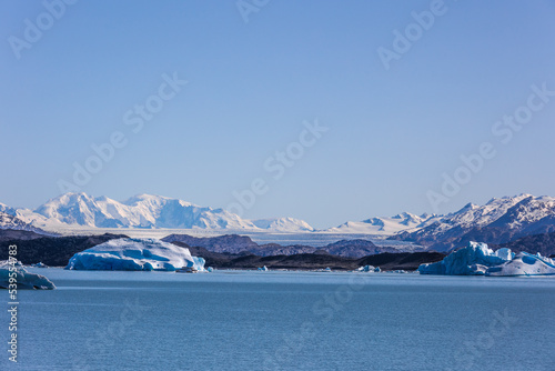 Paisaje apaisado glaciar entre montañas frente a lago photo