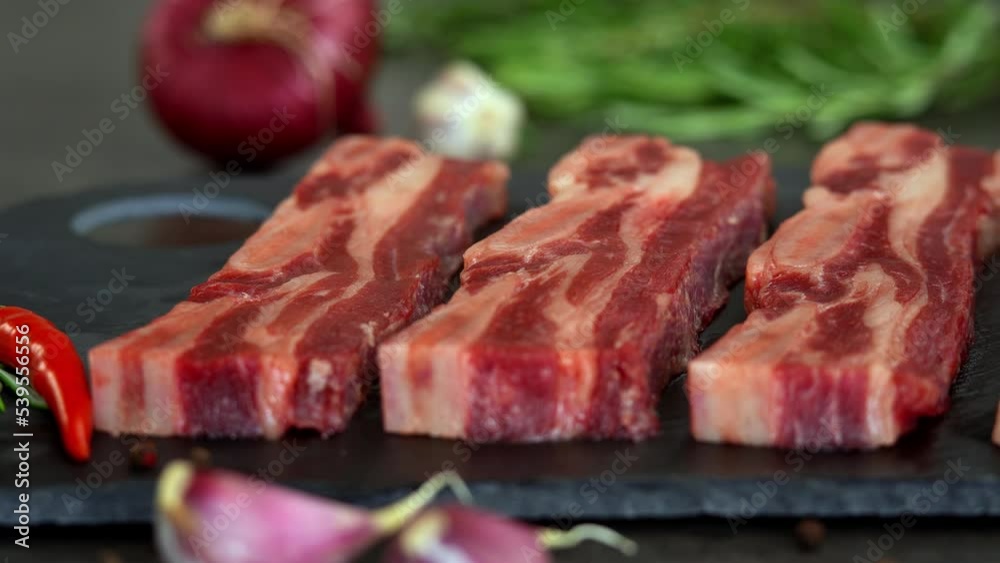 Camera movement on fresh raw beef ribs with seasoning and spices. Close up of pieces of beef steak on bone. Food