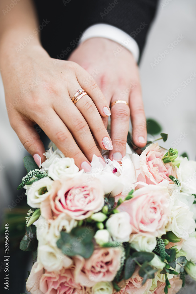 Beautiful young wedding couple posing with bouquet of flowers in hands Beautiful young wedding couple posing with bouquet of flowers in hands