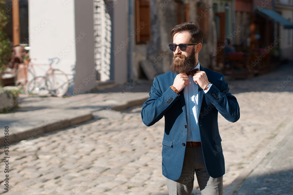 Stylish man with beard wearing a jacket, shirt adjusting his bow tie