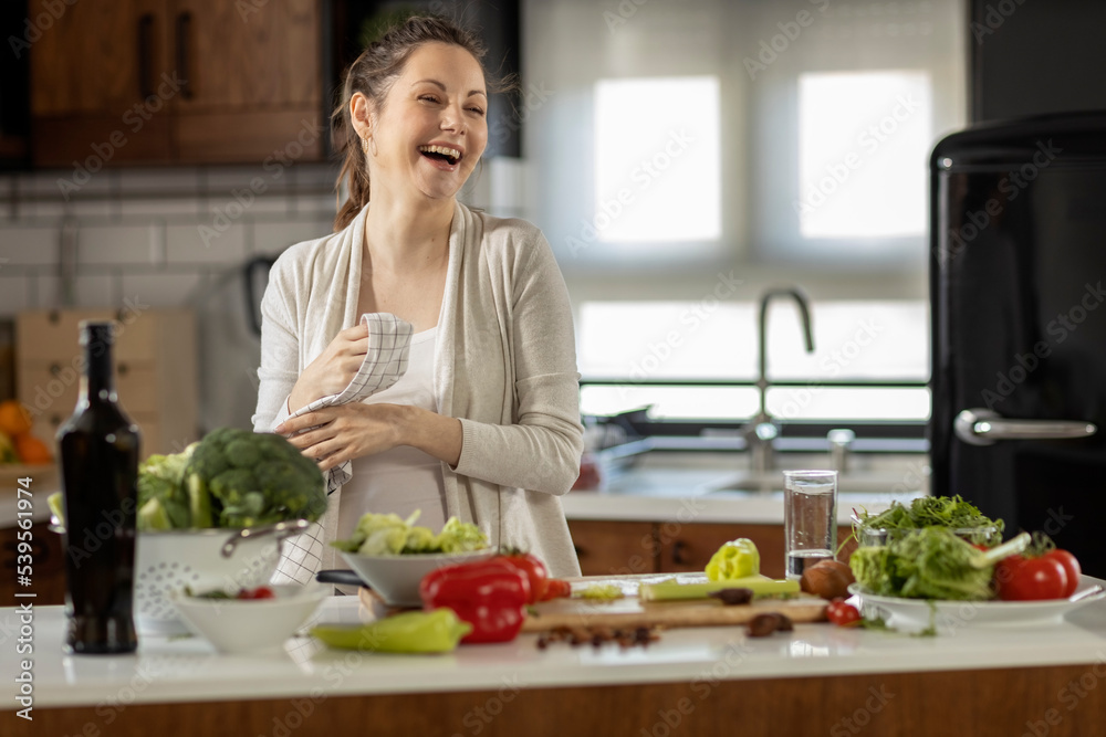 Happy pregnant woman prepare healthy food in the kitchen with smile on her face