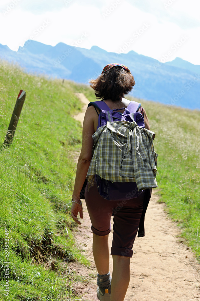 woman hiker while walking with backpack on shoulders in the trail in the mountains