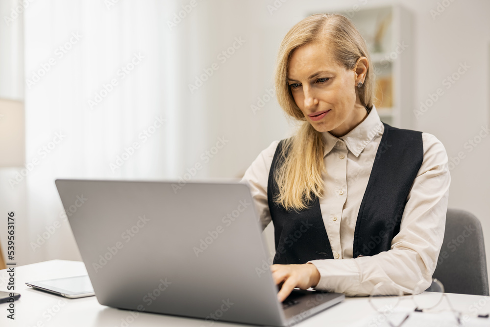 Blonde woman writer working with laptop at home, cheerful smiling lady typing novel at desktop, light home interior Blonde woman writer working with laptop at home, cheerful smiling lady typing novel at desktop, light home interior