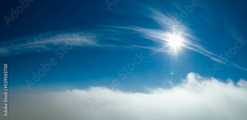 Aerial photo above clouds with Sun  clear sky above fast moving white cloudscape