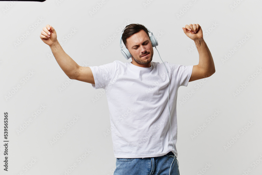 Cheerful tanned handsome man in basic t-shirt headphones listen favorite song dance smile posing isolated on over white studio background. Copy space Banner Mockup. Music Cool playlist concept