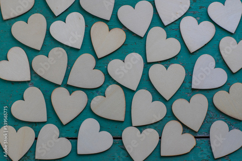Love Valentines day background, group of light wooden hearts spread on vintage blue green scratched table, flat lay one by one