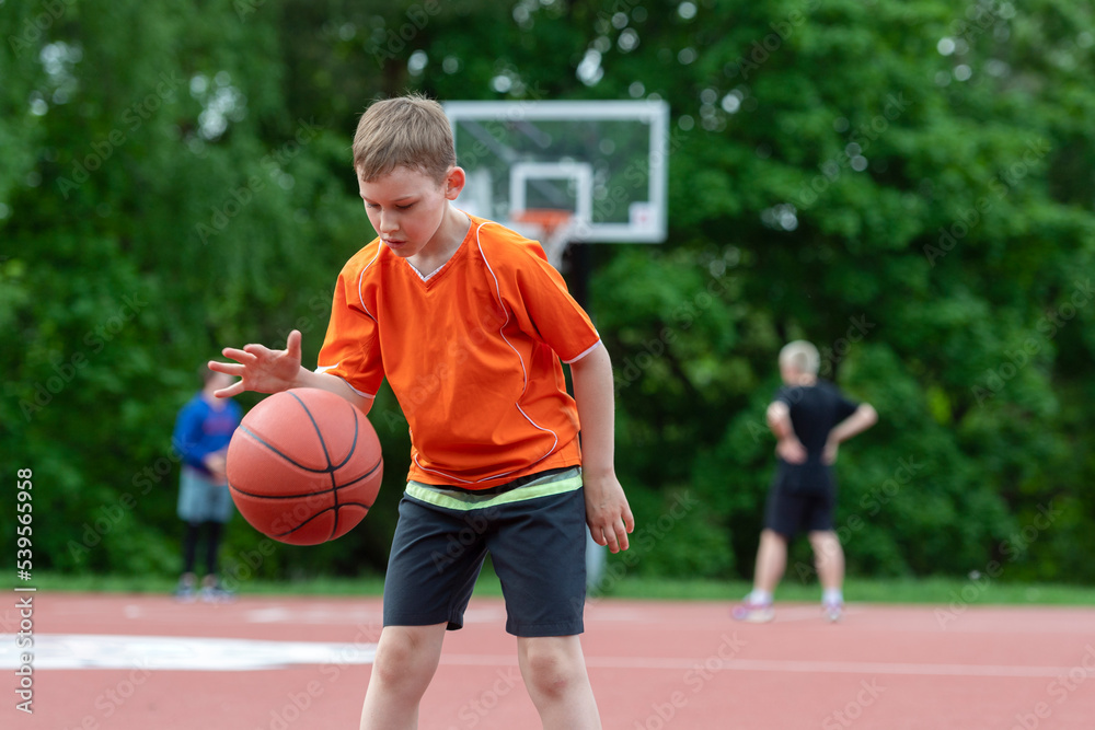 Naklejka premium Boy playing basketball on a park court. Concept of a sports lifestyle, training, camp, leisure, vacation. Horizontal sport theme poster, greeting cards, headers, website and app
