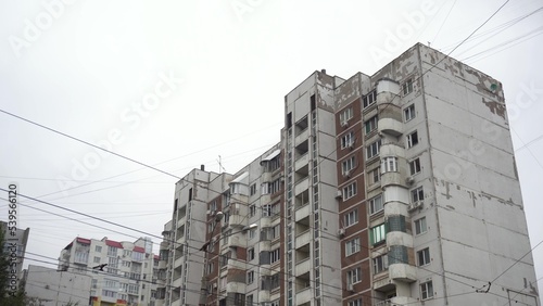 Large high soviet building panoramic view from bottom to top. An old dilapidated house from the times of the USSR. Concrete panel building against the background of gray clouds.