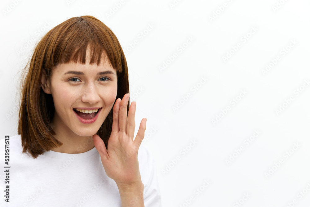 a happy, joyful woman stands in a white T-shirt, leaning towards the camera, smiling broadly as if she wants to tell a secret a happy, joyful woman stands in a white T-shirt, leaning towards the camera, smiling broadly as if she wants to tell a secret