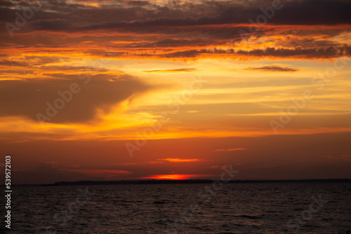 Amazing Black sea. Clouds and sand landscape background. Drama contrast sky and red sun. Golden blue hour at the ocean romantic evening. Tropical island summer paradise. Wild rest in camp.