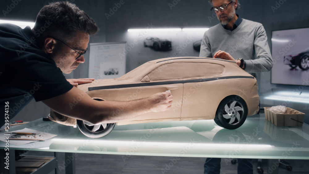 Two male automotive designers creating futuristic plasticine clay model of  car with professional tools. Future design of new generation electric car.  Working in modern car design studio. Stock Photo | Adobe Stock