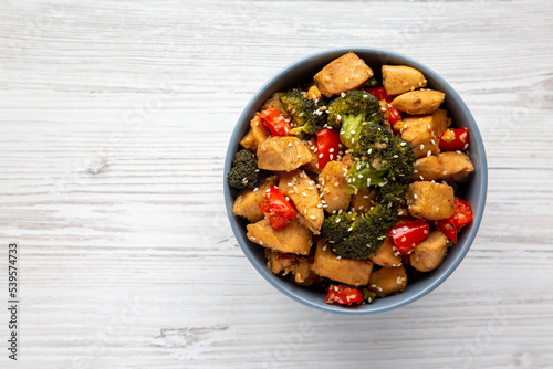 Homemade One-Pan Chicken And Broccoli Stir-Fry in a Bowl on a white wooden background, top view. Flat lay, overhead, from above. Copy space.
