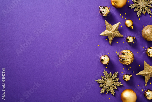 Glitter gold Christmas decorations  baubles  stars  snowflakes  confetti on purple background. Flat lay  top view.