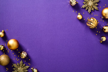 Purple Christmas background with golden balls and ornaments top view.