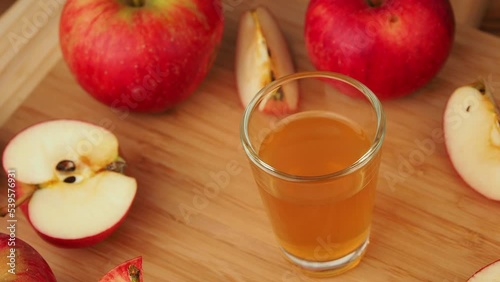 Apple cider vinegar is rotating on a wooden table.