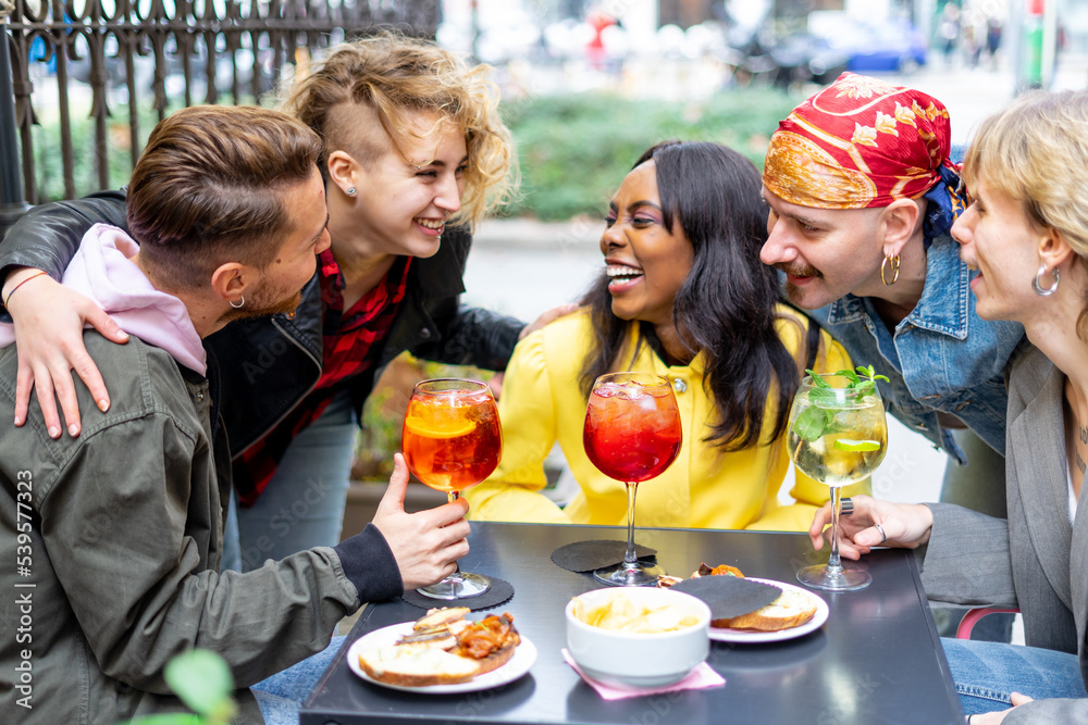Happy young friends toasting with drinks together at cocktail bar .