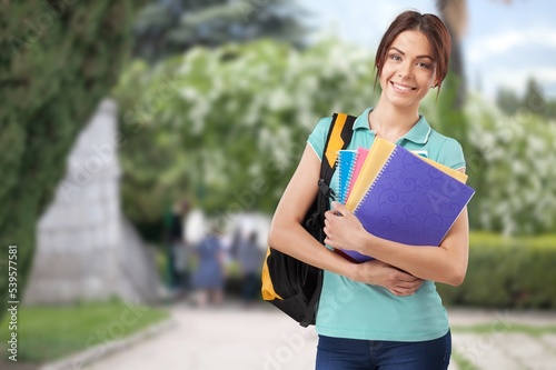 Portrait of a happy female student holding books and looking at natural outdoors © BillionPhotos.com