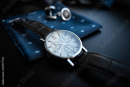 Business accessories. Mens watch and cufflinks isolated on black background.