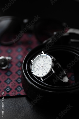 Business accessories. Mens watch and cufflinks isolated on black background.