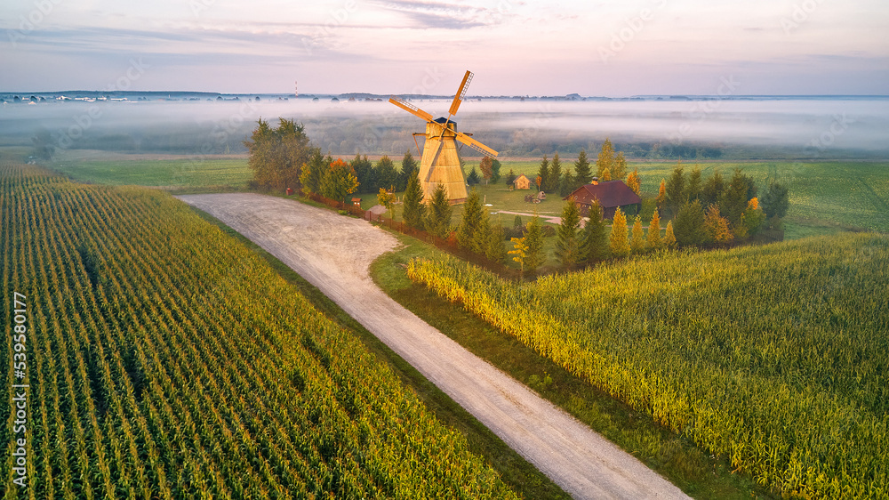 Traditional Wooden Windmill Morning Landscape. Rural colorful Sunrise, Foggy green fields. Dudutki village