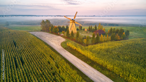Obraz na płótnie Traditional Wooden Windmill Morning Landscape. Rural colorful Sunrise, Foggy green fields. Dudutki village w salonie