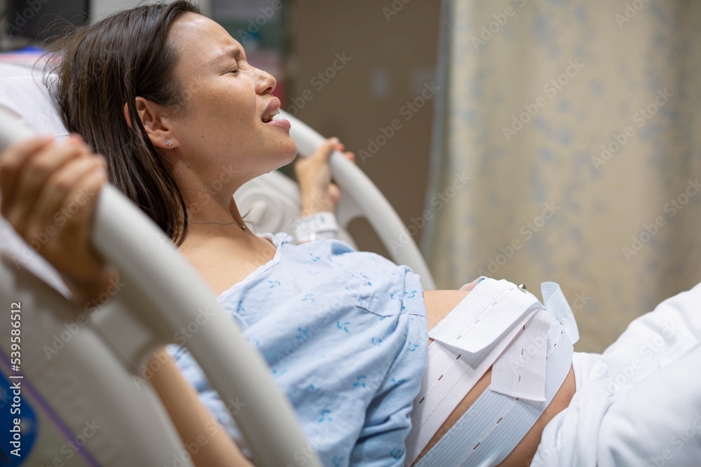 A pregnant woman lying in the hospital bed giving birth Labor A pregnant woman lying in the hospital bed giving birth Labor