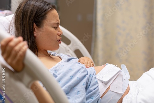 A pregnant woman lying in the hospital bed being monitored before childbirth. Induced labor. photo